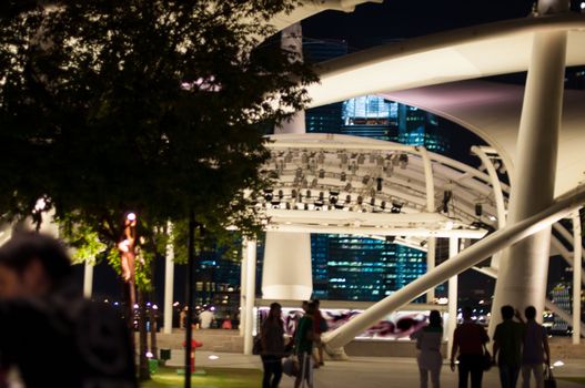 Singapore night scene with people at the marina walking in bright light