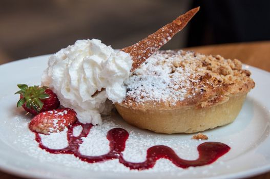 Richly decorated apple crumble with strawberries and cream
