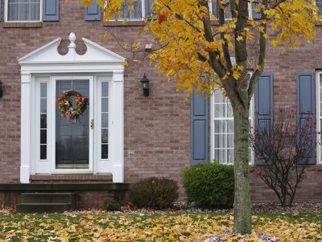 A fall wreath hangs on the door of a beautiful, new brick home in the autumn season 