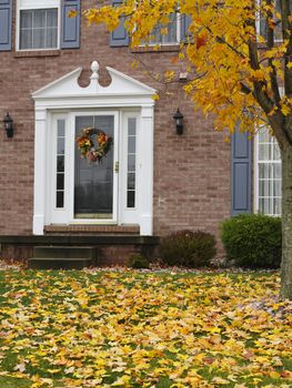A brick home's front doorway with seasonal wreath invites fall visitors