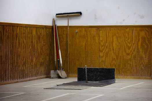 An indoor horseshoe pole with shovels and broom in rear