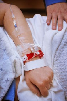 Married woman with infusion in arm in hospital with husband 