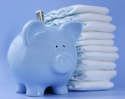 A baby blue piggy bank with a dollar bill stands in front of a tall pile of diapers against a baby blue background