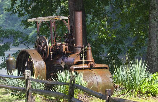 An old antique steam roller is parked in a grassy field