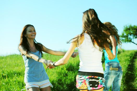 girlfriends round dance on a green grassy field