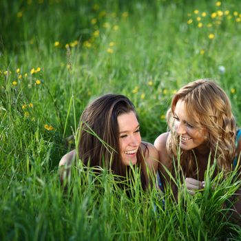 girlfriends lays on green grass and smile