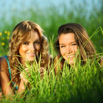 girlfriends lays on green grass and smile