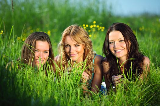 girlfriends lays on green grass and smile