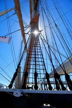 The sun peeks through the ropes and rigging of an old sailing ship