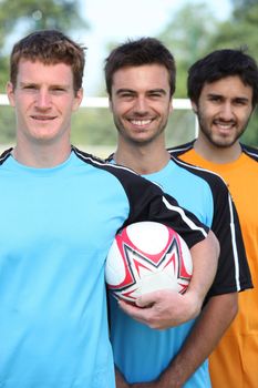 Three smiling young football players