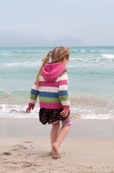 Little girl playing on the beach, sea nad sand