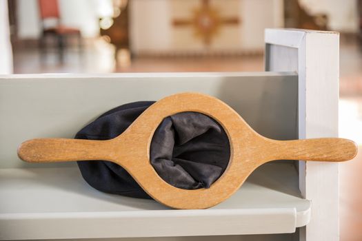 Empty collection bag lying on a wooden bench in a church