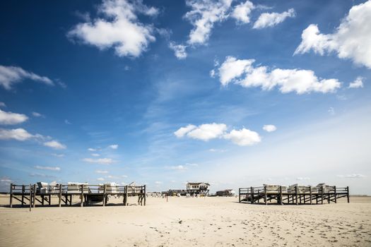 Sandy beach with beach chairs and buildings in St. Peter-Ording at the North Sea in Germany on a sunny day in spring