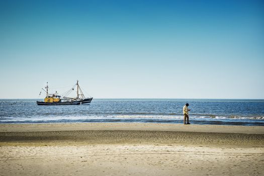 Trawlers in the North Sea. With a man on the beach of St. Peter-Ording on a sunny day