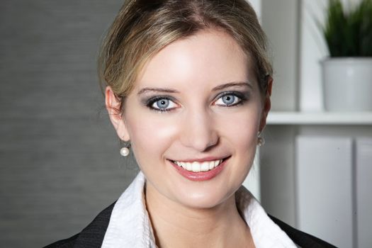 Portrait of a smiling businesswoman with neat blond hair in her office, headshot facing camera