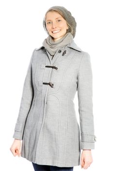 Young attractive woman wearing a grey coat and hat smiling at the camera.