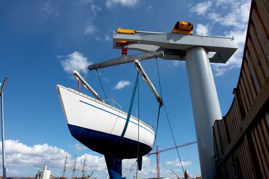 Sailboat lift up by a heavy industrial boat lifter for maintenance