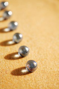 Abstract composition with few blue glass balls in a row on sand surface