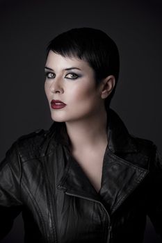 young woman in leather jacket, studio shot over black background