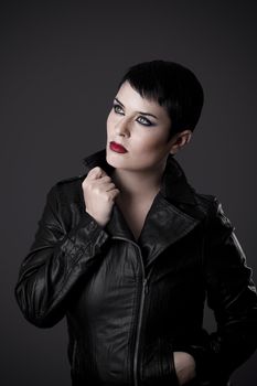 beautiful brunette young woman in black leather jacket, studio shot