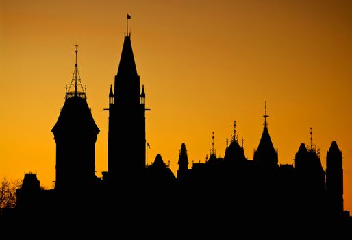 The canadian Parliament silhouette in front of an orange setting sun.