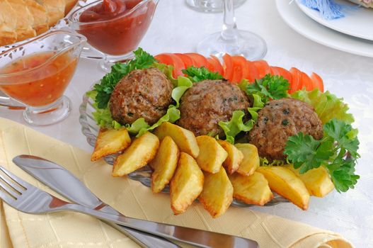 Meatballs with greens on salad leaves with potatoes and tomatoes