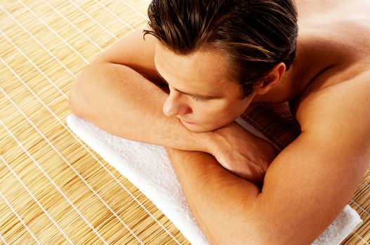 Man relaxing in a spa resort on mat. Relaxing with closed eyes