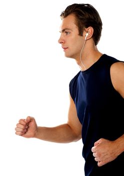 Fit athlete enjoying music in a jogging posture wearing sporty outfit