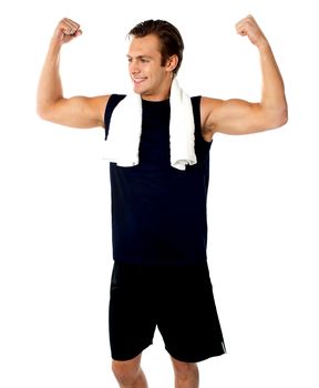 Young fit guy showing biceps. Towel around his neck