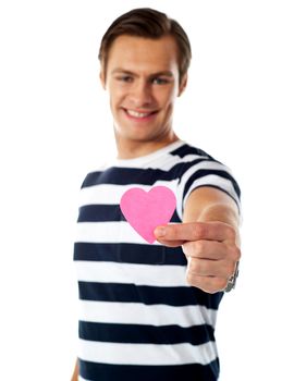 Young man ofering his paper heart to you. Isolated over white