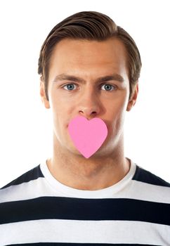 Good looking guy with heart shaped paper on his mouth. Closeup view