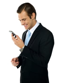 Male executive smiling as he reads message on his mobile. Isolated over white