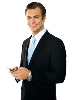 Corporate man messaging from cellphone, smiling at camera