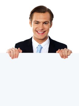 Smiling businessman holding a blank poster against white background