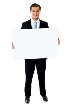 Portrait of smiling young businessman showing blank signboard