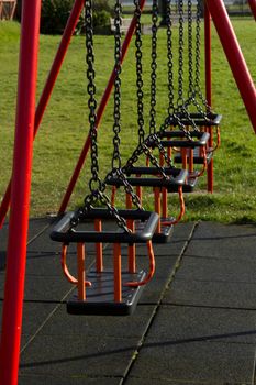 A row of swing seats on metal chains with safety bars and a protective padded floor.