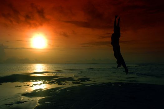 silhouette of a man jumping toward sunrise photographed by adding a filter gradation                            