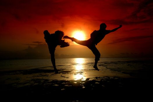 silhouette of two people who are fighting photographed before sunrise