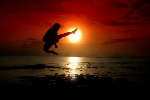 silhouette of a fighter is kicking with sunrise background