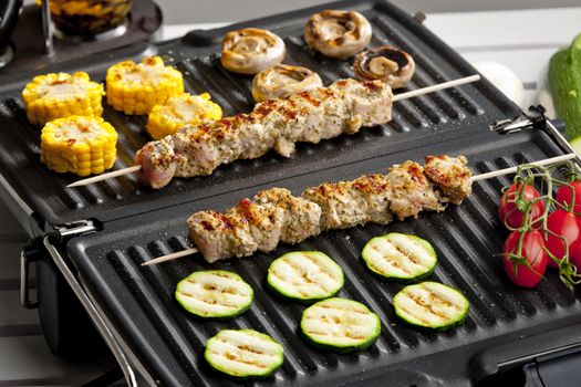 meat skewers and vegetables on electric grill