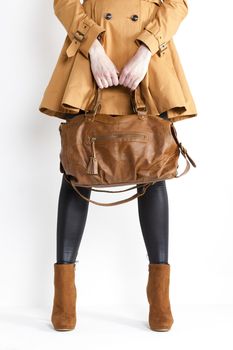 detail of standing woman wearing coat and fashionable brown shoes with a handbag