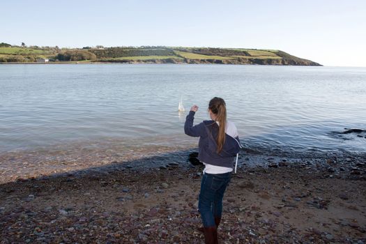 young girl throwing stones from the shore into the sea