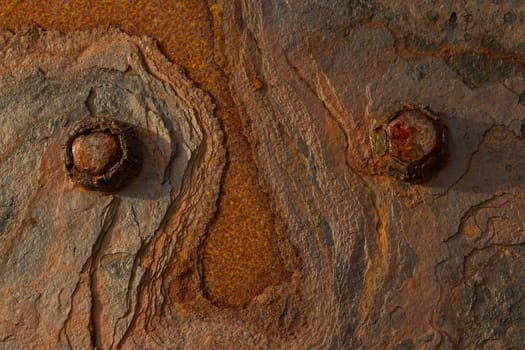 Rusting metal with bolts and a layered texture gives the appearance of a face.