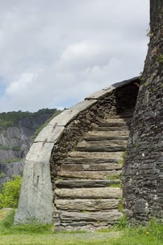 An historic stone built stairway with stone wall and coping slabs and a cloudy sky in the background.