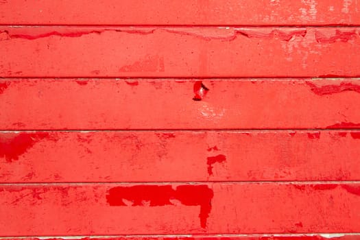 A background made of horizontal wooden slats painted in red flaking paint.