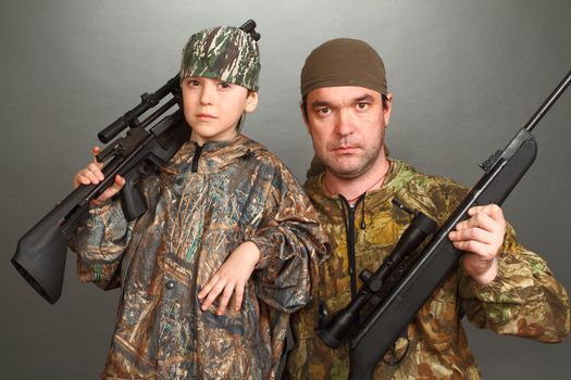 the boy and the adult man in a camouflage with rifles nearby in a shot, look in the chamber, a double 3