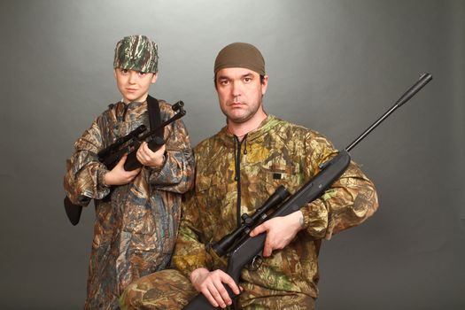 the boy and the adult man in a camouflage with rifles nearby in a shot, look in the chamber, a double 2