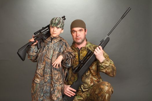 the boy and the adult man in a camouflage with rifles nearby in a shot, look in the chamber, a double 4