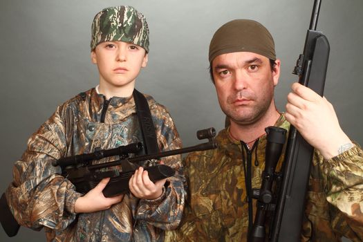 the boy and the adult man in a camouflage with rifles nearby in a shot, look in the chamber, a close up