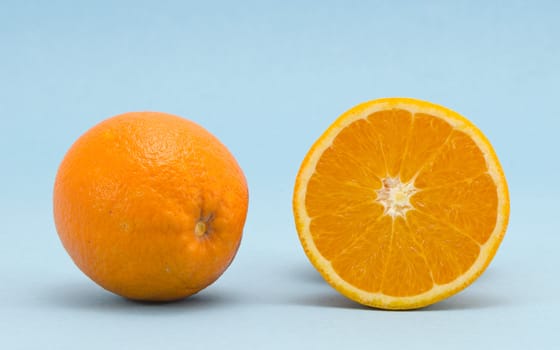 Oranges fruits full and sectioned on blue background. Healthy organic nutrition food objects.